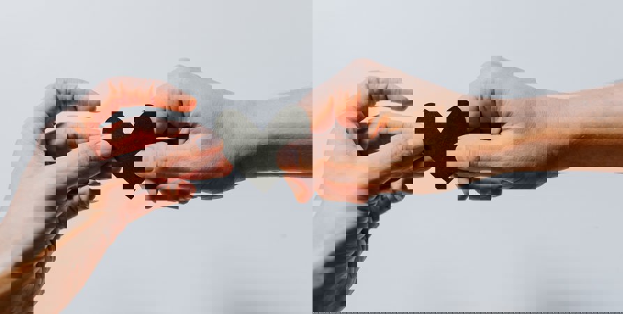 Två händer som håller ett hjärta i svart färg mellan sig. 